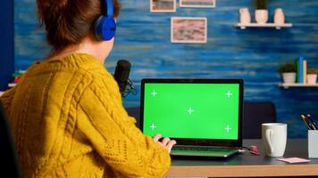 Blogger typing at laptop with green screen display recording new podcast series for audience. Broadcast show host streaming live content for social media using mochup, chroma key, izolated desktop photo