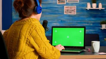 Influencer answering at messages working with green screen laptop during podcast in home studio. On-air production internet broadcast host streaming live content using chroma key mockup display photo
