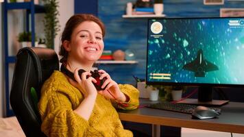 Professional esport woman gamer looking at camera smiling while compete in videogame playing space shooter game. Online streaming cyber performing on powerful personal computer during gaming tournament photo
