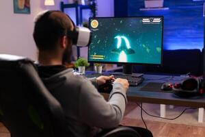 Professional gamer wearing virtual realilty headset and playing space shooter games with controller. Man streaming online videogames for esport tournament in room with neon lights photo