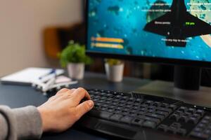 Hand of professional gamer on pro keyboard with RGB lighting during online gaming tournament. Home studio of esport game player using powerful gaming PC photo