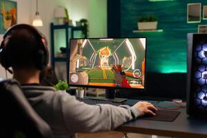 Videogamer looking into powerful computer playing virtual shooter game late at night in living room. Online streaming cyber performing during gaming tournament using technology network wireless photo