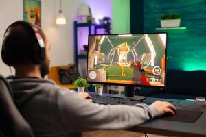 Pro player playing on computer videogame for tournament using professional headphones. Online streaming cyber performing during gaming competition using technology network wireless photo