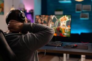 Competitive videogamer using powerful computer playing online videogame. Virtual streaming cyber streatching after performing gaming tournament using professional equipment. photo