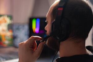 Close up portrait of pro esport player talking on headset with his teammates during online gaming virtual tournament. Home studio room with RGB neon lights, digital player photo
