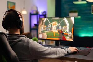 Professional player with headset playing videogame with modern graphics for shooter competition. Online streaming cyber performing during gaming tournament using technology network wireless photo
