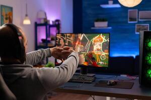 Competitive gamer streatching after playing digital videogames on powerful computer using pro headset. Online streaming cyber performing during gaming tournament in room with neon lights photo