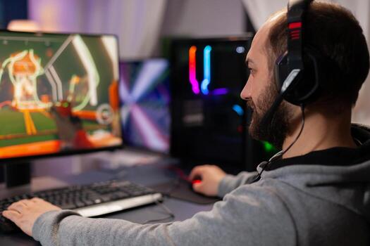 Digital player wearing headphones playing videogame with modern graphics for shooter game championship. Online streaming cyber performing during gaming tournament using powerful PC with RGB photo