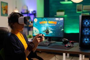 Competitive gamer looking into powerful computer playing online shooter game late at night with vr headset and console wireless. Virtual online streaming cyber performing during game tournament photo