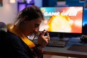 Game over for gamer playing games on powerful computer during night time in gaming studio at home. Woman streaming online videogames for esport tournament in room with neon lights photo