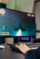 Closeup of Hand of player on professional keyboard with RGB during space shooter tournament. Pro gamer playing on gaming desk in home studio streaming online videogames photo