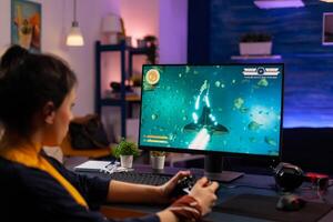 Videogamer playing graphics cyber space sitting on gaming chair using wireless console . Woman streaming videogames online for fun using RGB keypad and joystick for online championship photo