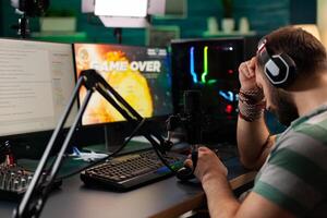 Side view of game over for streamer man with headphones playing online videogames with streaming chat open. Cyber performing on powerful computer in gaming room home using professional console photo