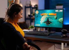 Winner player sitting on gaming chair at desk and playing space shooter games with joystick. Woman streaming online videogames for esport tournament in room with neon lights photo