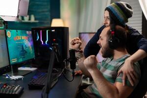 Streamer couple winning online space shooter competition using professional headset, microphone, keypad. Gamer playing online videogames with new graphics on powerful computer photo