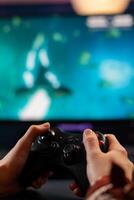 Close up of wireless joystick, gamer playing online videogames for live gamers tournament. Professional pro player streaming online game new graphics using powerful computer. photo