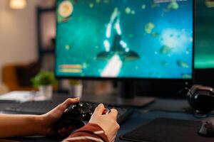 Close up of videogamer using wireless controller during live space shooter tournament in gaming home studio. Professional pro player streaming online game new graphics using powerful computer photo