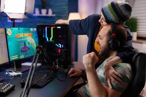 Players couple winning online videogames competition using professional equipment in home studio. Gamer playing games with new graphics on powerful gaming computer with RGB photo