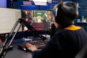 Pro gamer sitting on gaming chair at desk and talking into microphone for space shooter games competition. Woman streaming online videogames for esport tournament in room with neon lights photo