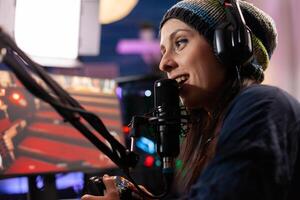 Close up of streamer woman talking into professional microphone in home studio. Online streaming cyber performing gaming tournament using technology network wireless photo
