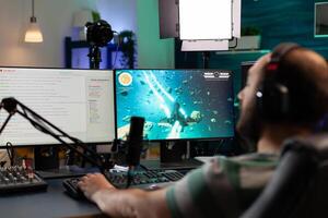 Streamer playing videogames and talking with teammates on streaming open chat. Cyber performing on powerful computer in gaming room home using professional equipment photo