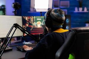Caucasian player wearing headphones talking with other players while playing professional shooter games in online tournament. Gamer making online videogames with new graphics on powerful computer photo