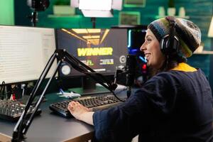 Back view of upseted streamer playing game competition using professional setup with streaming chat open. Gamer sitting on gaming chair using wireless controller and professional headphone photo