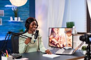 Vlogger talking with her audience while making online show from living room. Speaking during livestreaming, blogger discussing in podcast wearing headphones. photo