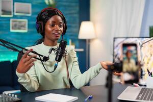 Influencer making online internet content for web subscribers in home podcast studio. Speaking during livestreaming, blogger discussing in podcast wearing headphones. photo