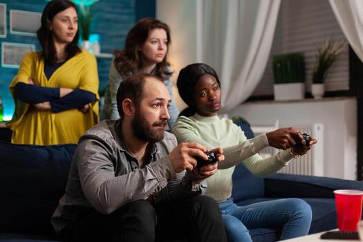 Man playing games with multi ethnic friends using wireless controller. Mixed race group of people hanging out together having fun late at night in living room. photo