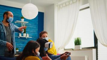 Black woman experiencing virtual reality headset playing games wearing face mask while friends having fun drinking beer. respecting distancing wearing face mask to prevent infection with virus, photo