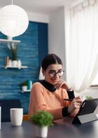 Graphic designer working on creative illustration using graphic digital tablet holding drawer pen in hand retouching draw. Focused student sitting at desk table in living room photo