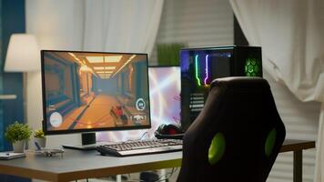 Empty room with RGB powerful personal computer for online videogames and gaming chair, first-person shooter game on screen. Cozy room with modern design is lit with warm and neon light. photo