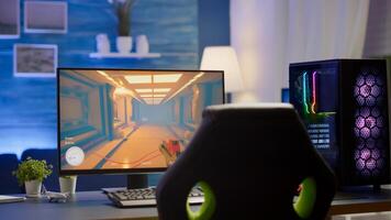 RGB powerful personal computer gamer rig with first-person shooter game on screen. Monitor stands on table in home gaming room. Cozy room with modern design is lit with warm and neon light. photo