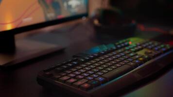 Close up of professional keyboard with RGB lighting prepared for streaming online tournament, display with first person shooter playing on it. Gaming studio of esport game with powerful computer photo