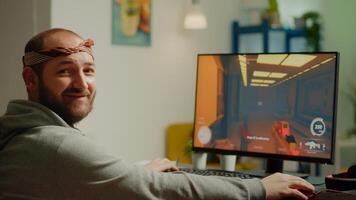 Pro man gamer turning head looking at camera smiling playing FPS shooter videogame during gaming championship in cyberspace. Esports player performing on powerful computer in online tournament photo