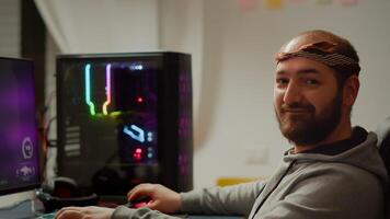 Portrait of young pro gamer man sitting at powerful personal computer looking into camera. Concentrated cyber playing first-person space shooter online game performing during gaming tournament photo