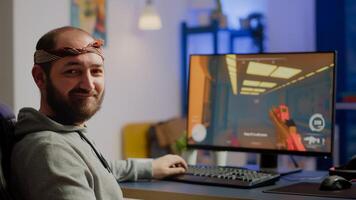 Pro cyber man looking at camera before playing space shooter videogames using professional RGB keypad on powerful computer. Professional player performing during online gaming championship late night photo