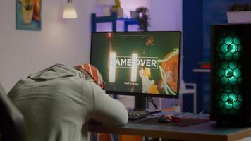 Game over for sad gamer playing shooter games on powerful computer using RGB keyboard in gaming room. Defeated man with headphones streaming online cyber performing through online tournament photo