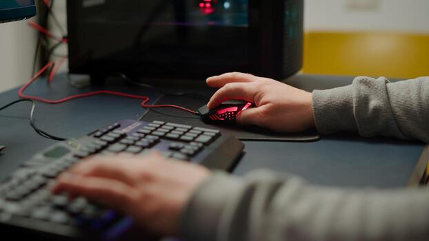 Close up hands shot of man player typing on RGB keyboard buttons while playing online shooter game. Virtual shooter game performing in cyberspace, esports gamer esports online tournament photo