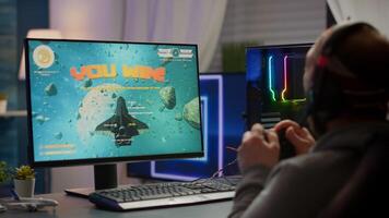 Winner gamer sitting on gaming chair playing space shooter games with wireless controller. Pro cyber man streaming online games for esport tournament on RGB powerful personal computer photo