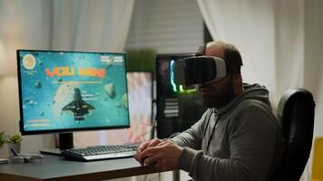 Videogame player with VR headset raising hands after winning space shooter competition. Professional pro gamer playing online games with new graphics on powerful computer from gaming room photo