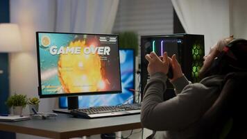 Focused pro cyber keeping hands on head after losing space shooter game using wireless joystick. Angry gamer wearing professional headset for online esports championship sitting on gaming chair photo