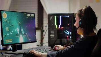 Addicted lady playing space shooter game using headphones ,wireless joystick and RGB powerful personal computer. Cyber gamer with headset and joypad performing virtual games at gaming championship photo