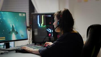Pro woman game r using headset and powerful computer playing online space shooter games in gaming room. Virtual streaming cyber wearing headphones performing online tournament photo