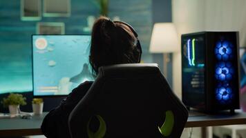 Back view of digital pro player playing online space shooter game competition using RGB prowerful personal computer. Professional cyber woman gamer with headset streaming gaming championship photo