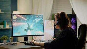 Focused player sitting on gaming chair playing online space shooter games using RGB keyword. Professional pro cyber streaming online game new graphics using powerful personal computer photo