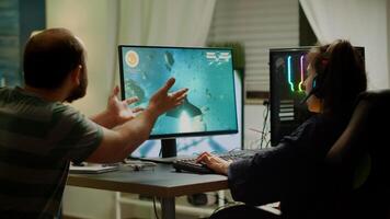 Excited couple players wining space shooter game during virtual competition tournament using professional headset. Excited online streaming cybers performing gaming using RGB powerful computer photo