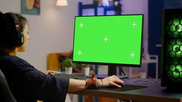 Pro woman player gaming on powerful computer with green mock up chroma key screen while streaming online competition. Gamer using pc with greenscreen isolated desktop streaming shooter games photo