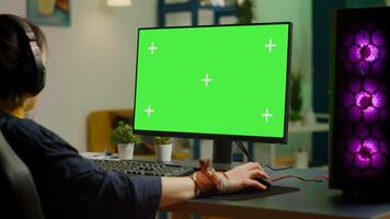 Woman gamer streaming online games on powerful computer with green screen mock up, chroma key display. Cyber player using professional pc with isolated desktop streaming shooter games in headset photo